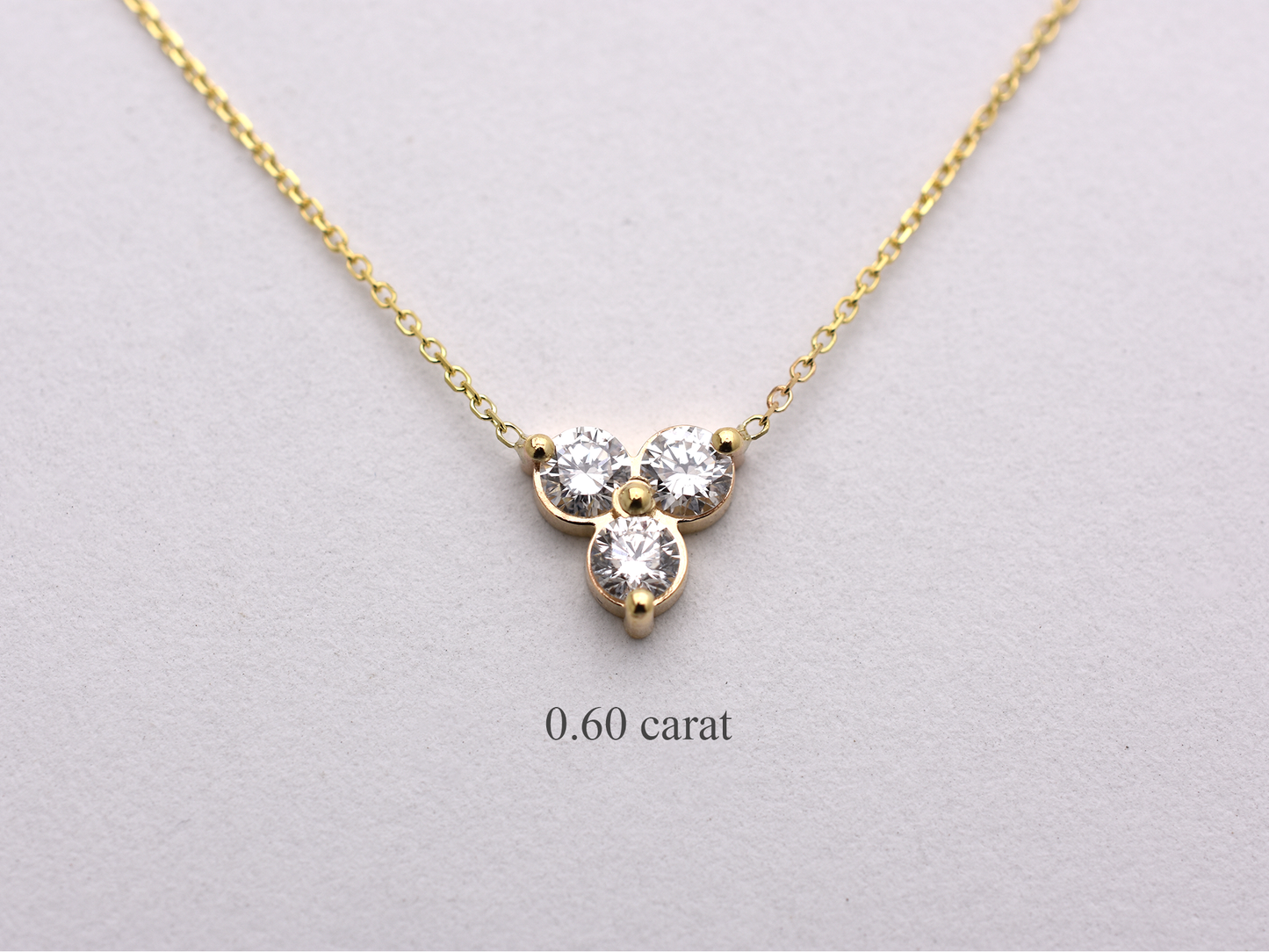 14k yellow gold necklace with a three-stone pendant of round brilliant cut 0.60  carat diamonds  on a white background