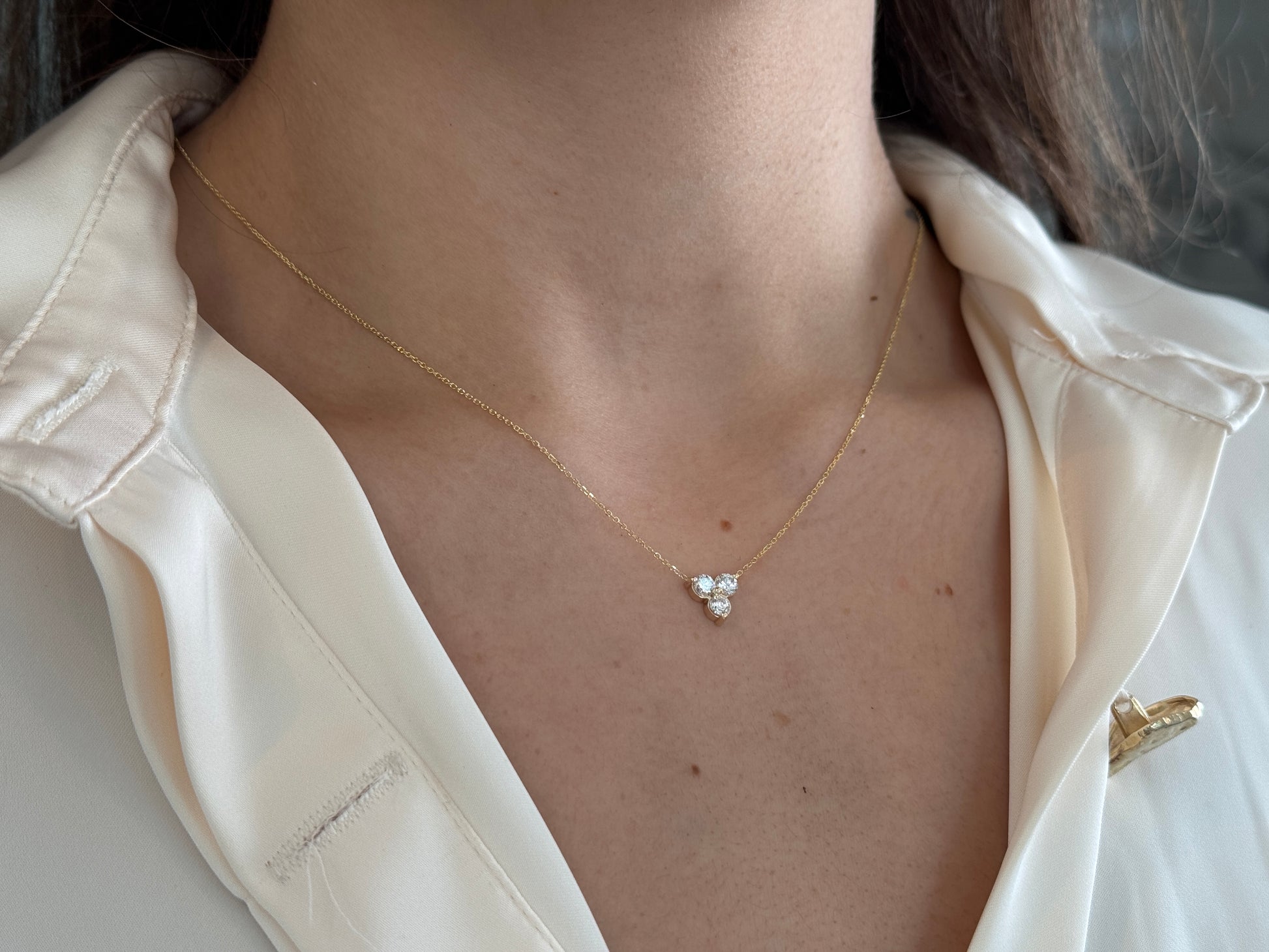 14k yellow gold necklace with a three-stone pendant of round brilliant cut diamonds  on a model