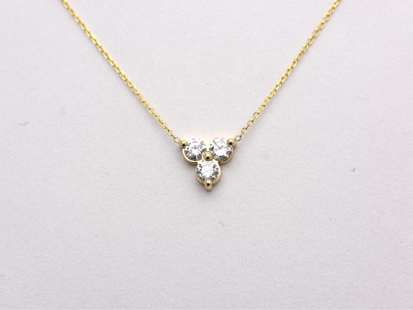 14k yellow gold necklace with a three-stone pendant of round brilliant cut 0.60  carat diamonds  on a white background