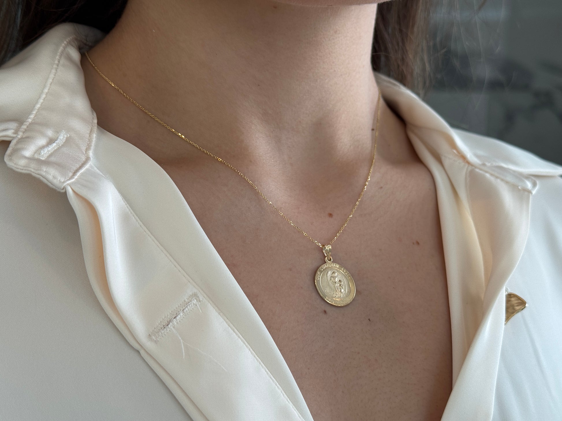 14k solid gold 17 mm Guardian Angel charm necklace .perfect for layering everyday look displayed on a model wearing a white shirt . intended for all ages and for men and ladies