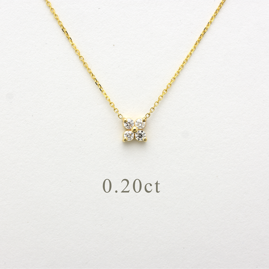 Close-up of a delicate 14K yellow gold chain necklace featuring a small, clover-shaped cluster pendant. The pendant consists of four brilliant round-cut diamonds totaling 0.20 carats, set closely together to create a tiny floral design. The necklace is displayed on a white background.