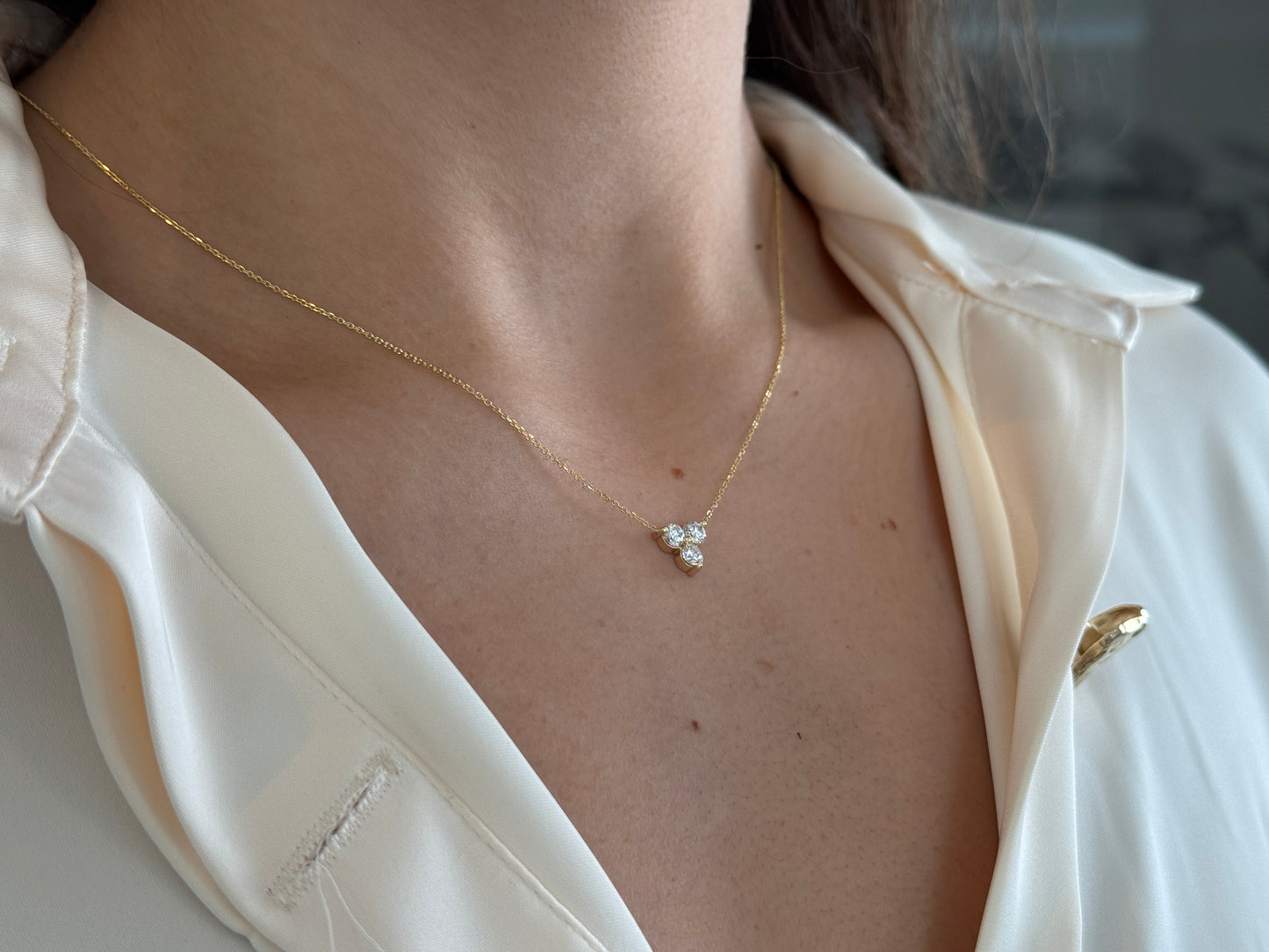 14k yellow gold necklace with a three-stone pendant of round brilliant cut diamonds  on a model