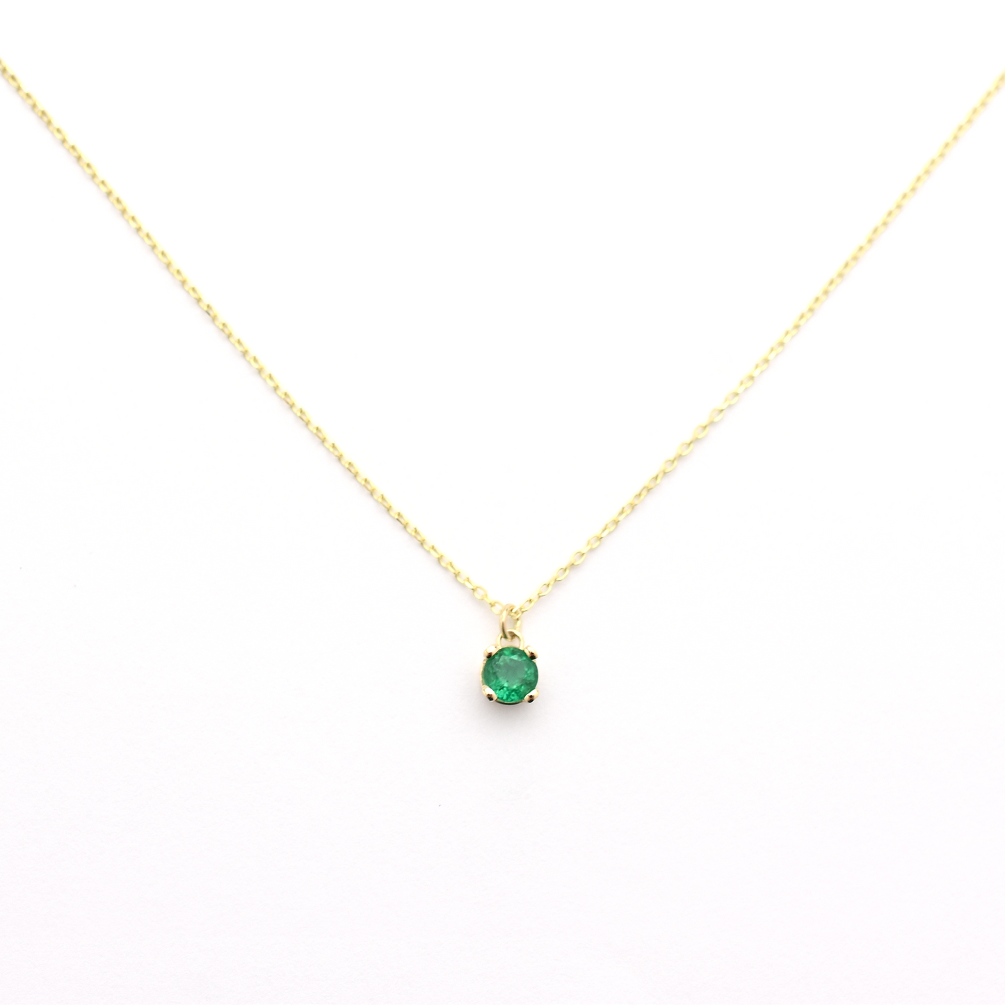 A 14k gold necklace with a single emerald stone pendant.