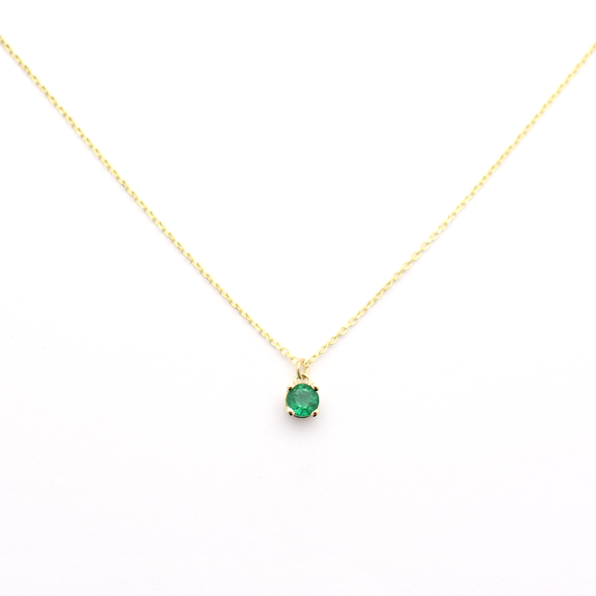 A 14k gold necklace with a single emerald stone pendant.
