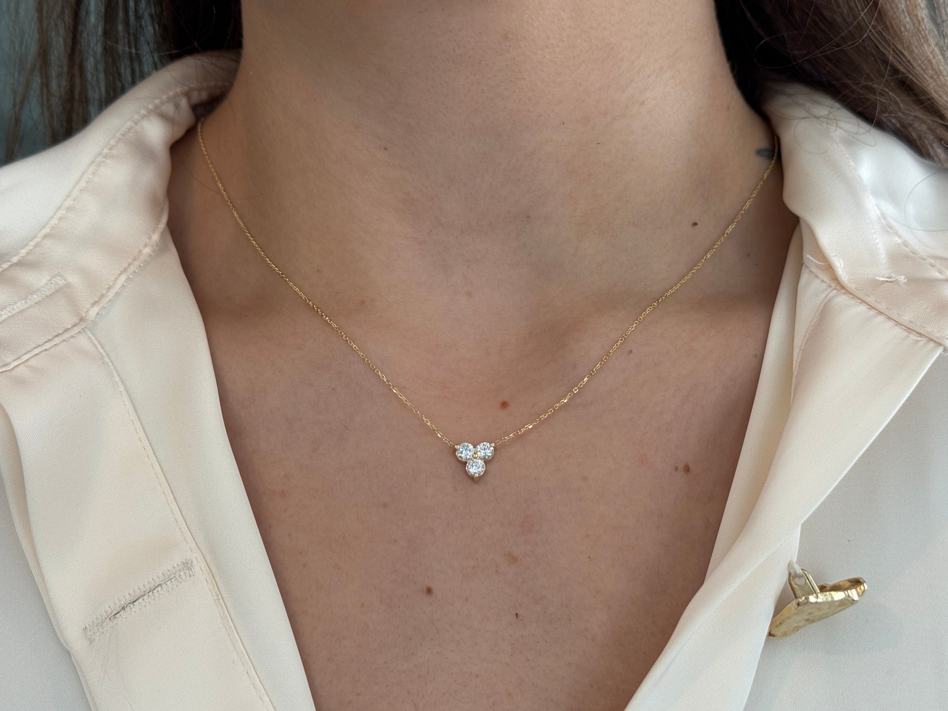 14k yellow gold necklace with a three-stone pendant of round brilliant cut diamonds  on a model