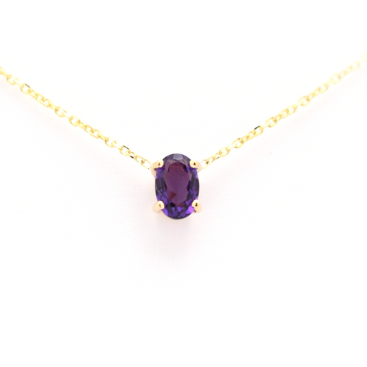 A 14 k gold necklace with a natural oval Amethyst gemstone prong set on it, displayed against a white background.
